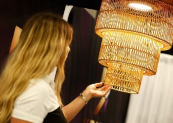 Woman admiring a large, woven, golden hanging light fixture.