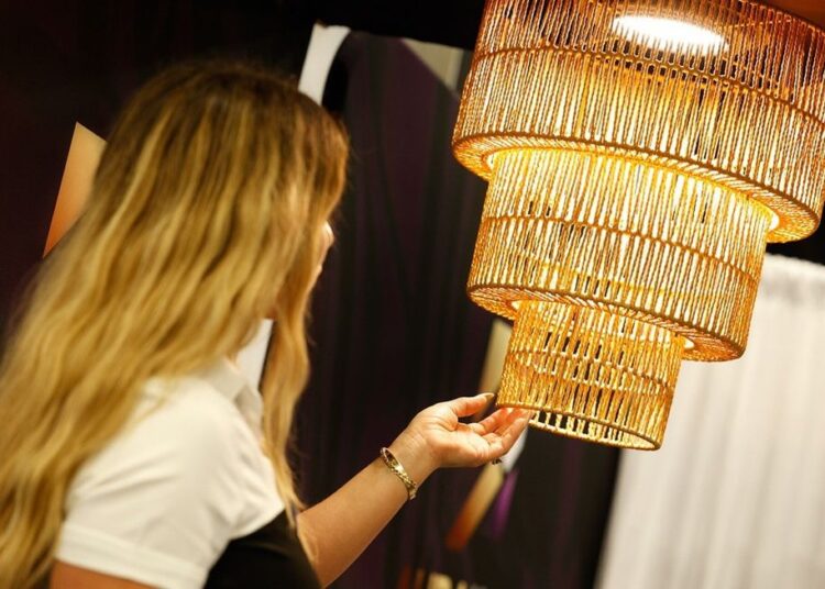 Woman admiring a large, woven, golden hanging light fixture.