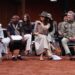 Mary and Frederik sit on chairs watching a man perform a ceremonial dance