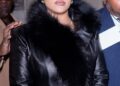 Rihanna in a black leather coat with a fur collar.