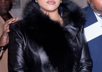 Rihanna in a black leather coat with a fur collar.