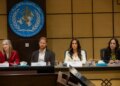 Prince Harry with a stern face sitting at a roundtable