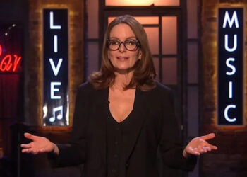 Tina Fey wears a black dress and talks during the monologue on SNL UK.
