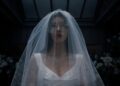 A woman wearing a white veil over her face.