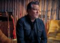 John Garcia sits in a room with guitars.