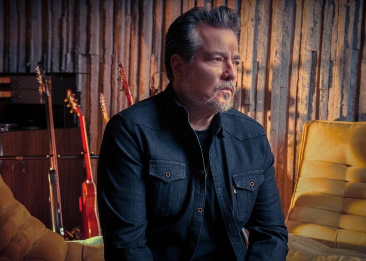 John Garcia sits in a room with guitars.