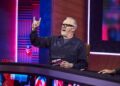 Greg Davies making a rock and roll sign with his hands whilst holding a card.