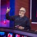 Greg Davies making a rock and roll sign with his hands whilst holding a card.