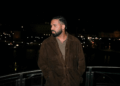 Drake posing on a balcony at night