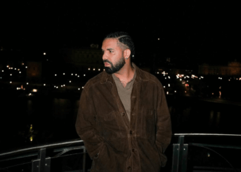 Drake posing on a balcony at night