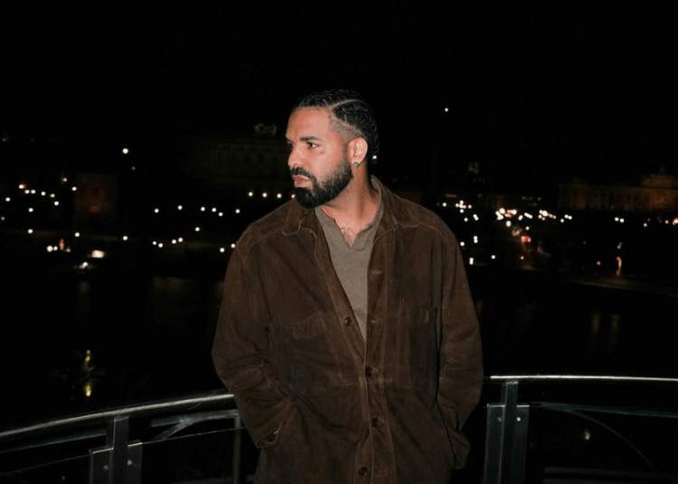 Drake posing on a balcony at night