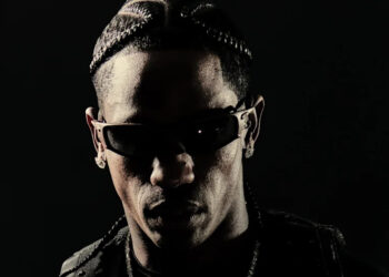 Travis Scott with braided hair and sunglasses, set against a dark background.