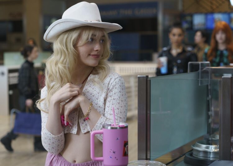 A woman in a white cowboy hat smiles.