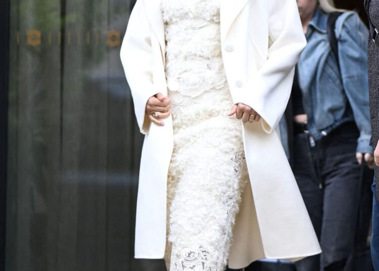 Woman exiting a building in elegant attire.