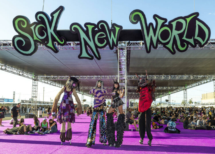 Stilt walkers in costume await photo opportunities during the Sick New World festival at the La ...