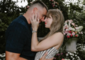 Couple sharing a kiss in a floral garden setting.