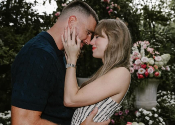 Couple sharing a kiss in a floral garden setting.
