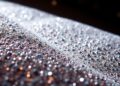 An extreme close-up of shimmering, high-contrast sequins and glittering textures, conceptually representing the luxurious and glamorous world of celebrity sightings in New York City.