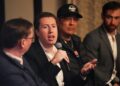 A man in a suit speaks into a microphone.