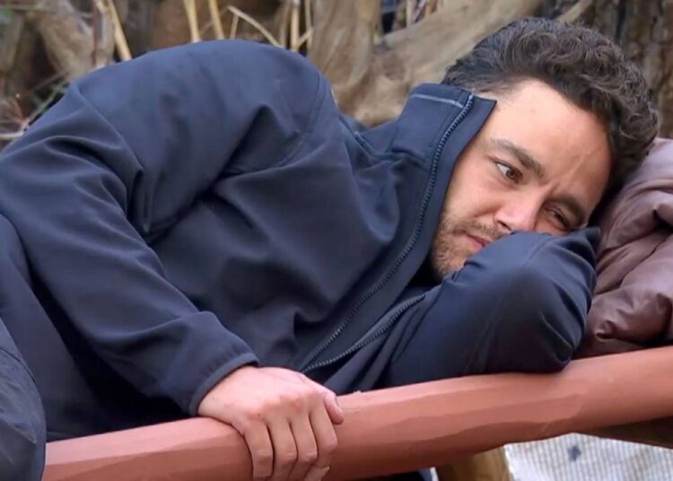 Adam Thomas lying on a camp bed on I'm A Celebrity