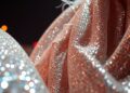 An abstract close-up photograph featuring a textured, high-contrast pattern of shimmering sequins and metallic fabrics, evoking the glamour and energy of the Coachella music festival.