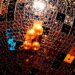 An abstract close-up photograph showcasing the shimmering, glittering textures of sequins and disco ball fragments, captured in dramatic high-contrast studio lighting to evoke the energy and opulence of a vintage carnival celebration.