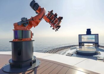 Robotic thrill ride on cruise ship deck with ocean view and outdoor screen.