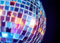 An abstract close-up photograph of shattered disco ball fragments reflecting dramatic, high-contrast studio lighting, conveying the glamour and excitement of Miami's music and entertainment culture.