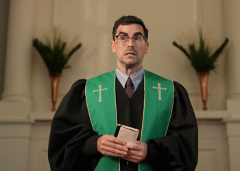 Individual in clerical attire holding a book.