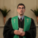 Individual in clerical attire holding a book.