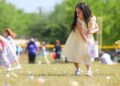 A child puts an easter egg into a basket.