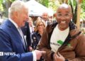The King (left) and CEO of Harlem Grown Tony Hillery (right) both smile during an exchange in front of onlookers while on an outdoor tour of the organisation in Upper Manhattan on Wednesday.