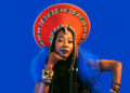 Fatoumata Diawara — Photo by Marcello Perego. Fatoumaa wearing a blue dress and a traditonal red headdress.