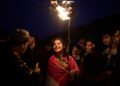 A Kurdish woman in traditional dress holds a lit torch during Nowruz, the Persian New Year, on a hill overlooking the town of Akra in the autonomous Kurdistan Region of Iraq, Friday, March 20, 2026. (AP Photo/Leo Correa)