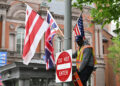 A worker puts up flags on a lamppost near the White House ahead of a visit by Britain's King Charles III, in Washington, DC on April 25, 2026.