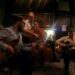 A musical trio of four white men playing jazz guitar and base. Straight Up!