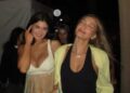 Two women in casual outfits walking together at a social event.