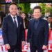 Ant & Dec stood next to each other wearing suits, smiling ahead on a red carpet.