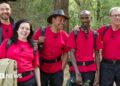 Adam Thomas, Scarlett Moffatt, Craig Charles, Mo Farah and Harry Redknapp standing together, smiling and all wearing red I'm A Celebrity T-shirts