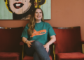 Abbie McCarthy sits on a chair with a pop art print of Marilyn Monroe behind her