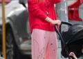 Woman walking with a stroller in casual attire.