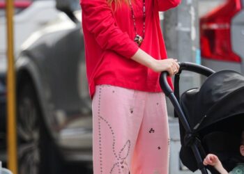 Woman walking with a stroller in casual attire.