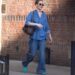 Person walking on a sidewalk near a brick building.
