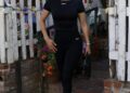 A person walking out of a café dressed in black athletic wear.
