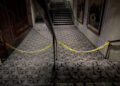 Yellow police tape blocks off a carpeted hallway with two stairways.