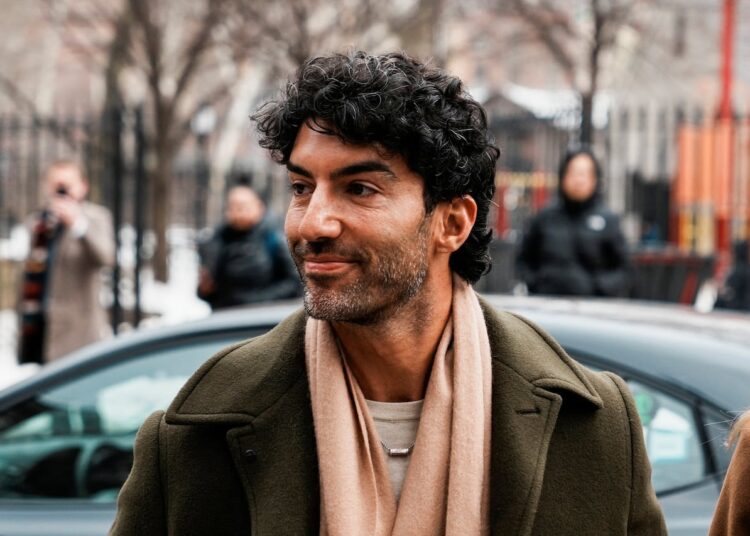 A man in a green wool coat outside a car.