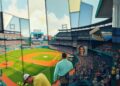 A cubist, geometric painting depicting a baseball game or match, with the players and field broken down into sharp, overlapping planes of color and shape, conveying the dynamic energy of the sport.