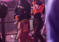 Two individuals walking in a crowd at a nighttime event.