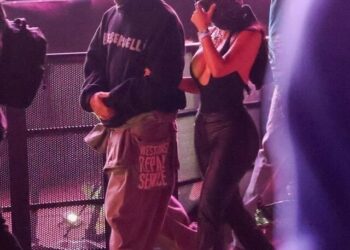 Two individuals walking in a crowd at a nighttime event.