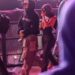 Two individuals walking in a crowd at a nighttime event.